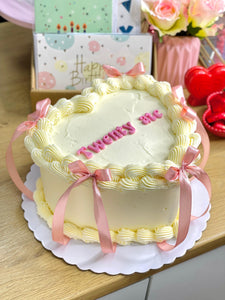 Corazón blanco con lazos y texto rosa disponible desde 8/12 porciones